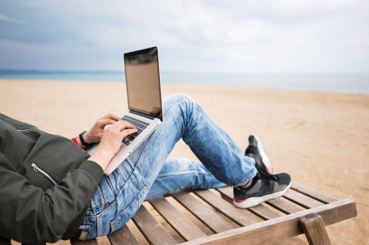 Ein digitaler Nomade mit Laptop am Strand